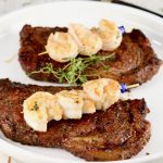 steak and shrimp on a white plateSurf and Turf is the ultimate dinner for entertaining guests or date night. Grilled ribeye steaks topped with garlic butter shrimp is a hearty and delicious meal that is sure to impress.