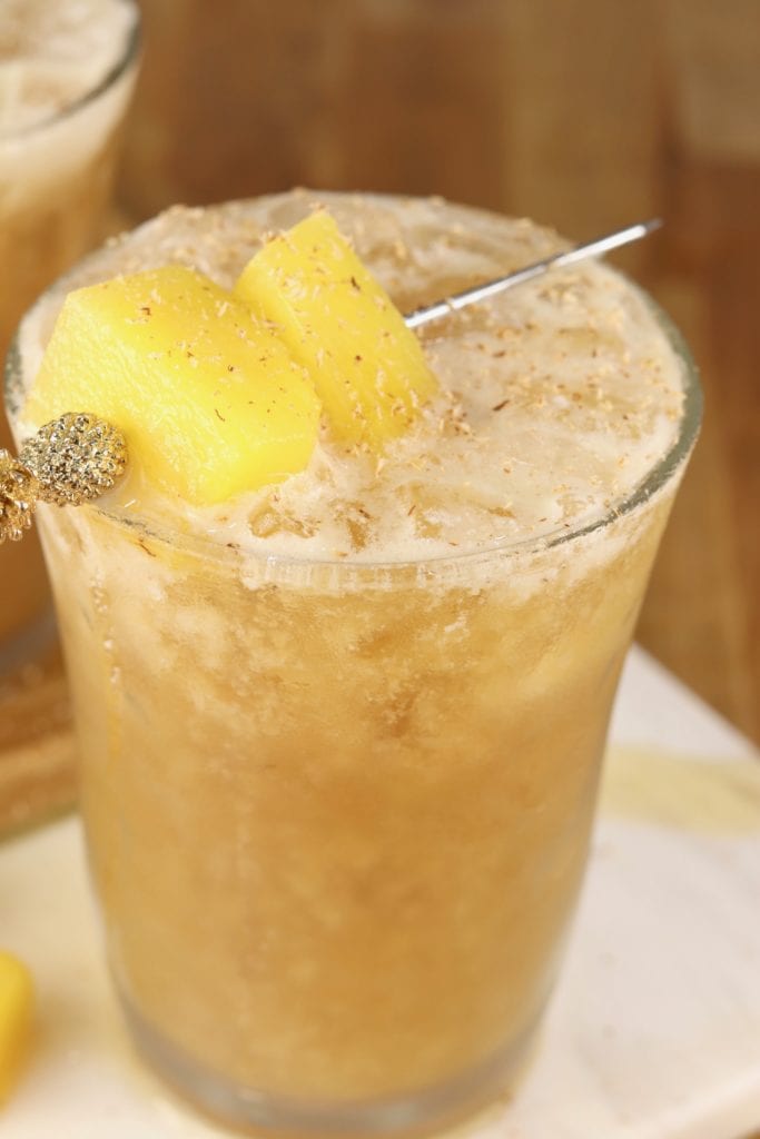 Dark rum and pineapple Painkiller cocktail garnished with pineapple and nutmeg.