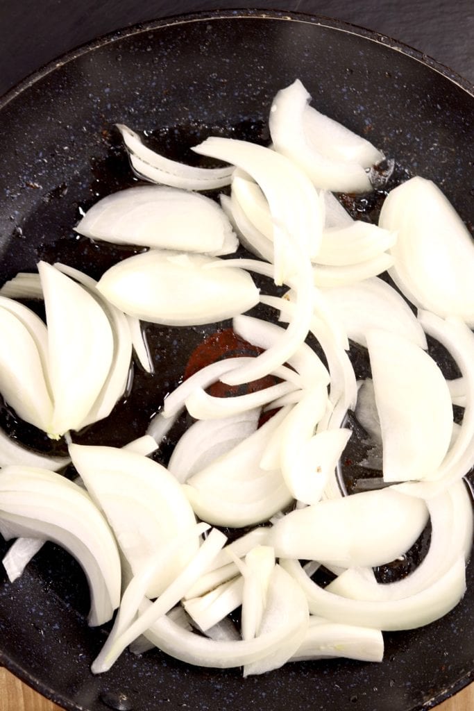 sliced onions in a skillet for fried cabbage