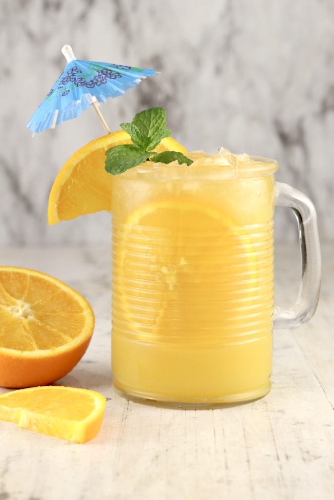 Brass Monkey Orange Juice cocktail garnished with an orange slice, drink umbrella and mint