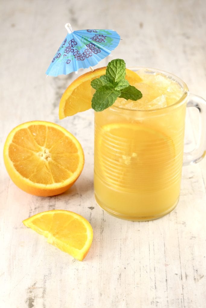 Mug of Orange Cocktail with vodka and rum, garnish of orange slice, mint and an umbrella