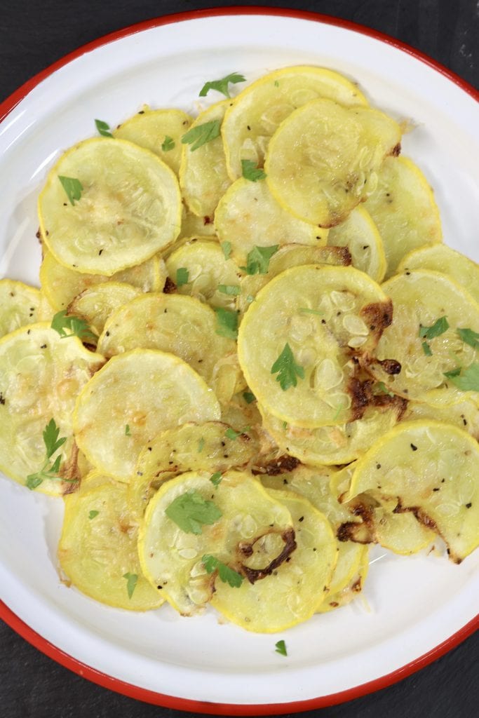 Parmesan Squash is a super simple and delicious side dish to make with yellow squash, Parmesan cheese and a few spices. Baked in the oven for the ultimate low-carb side dish or snack. Parmesan Squash on a red rimmed white plate