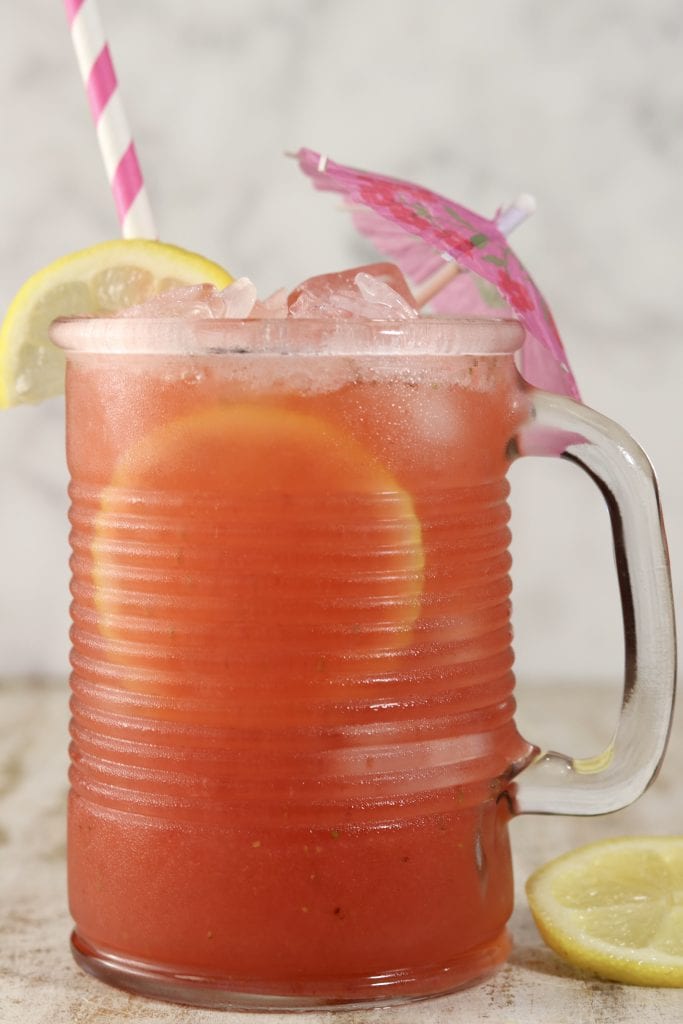 Mug of strawberry lemonade, drink umbrella, pink straw, lemon slice garnish