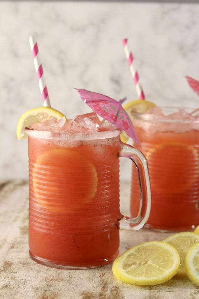 Strawberry Lemonade in 2 glasses with lemon garnish and drink umbrella