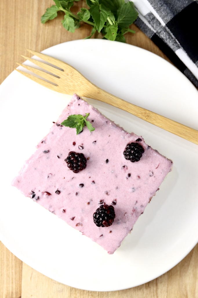 Slice of blackberry sheet cake with a bamboo fork on a white plate