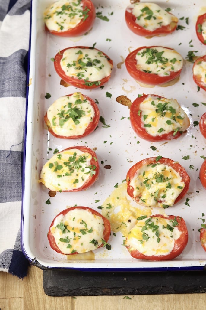 Cheesy Baked Tomatoes with fresh herbs on a white baking sheet