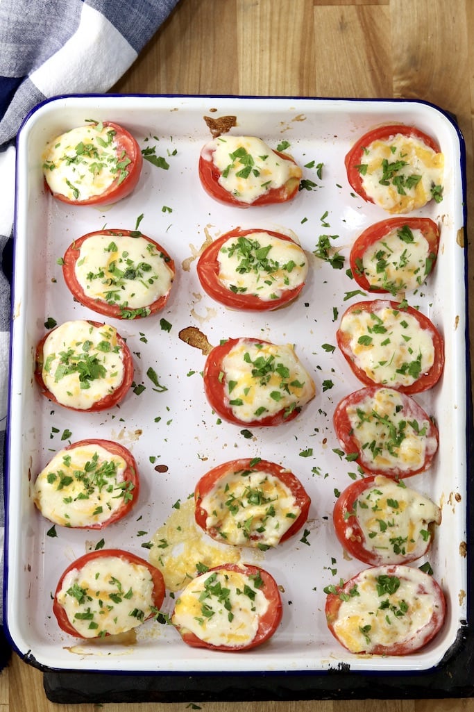 Baked Tomato halves with creamy cheese filling and fresh herbs in white baking pan