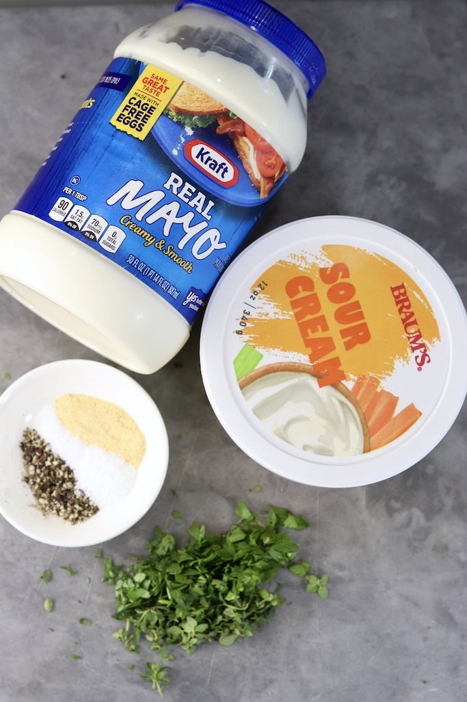 Ingredients for creamy salad dressing: mayonnaise, sour cream, garlic, salt and pepper plus fresh herbs
