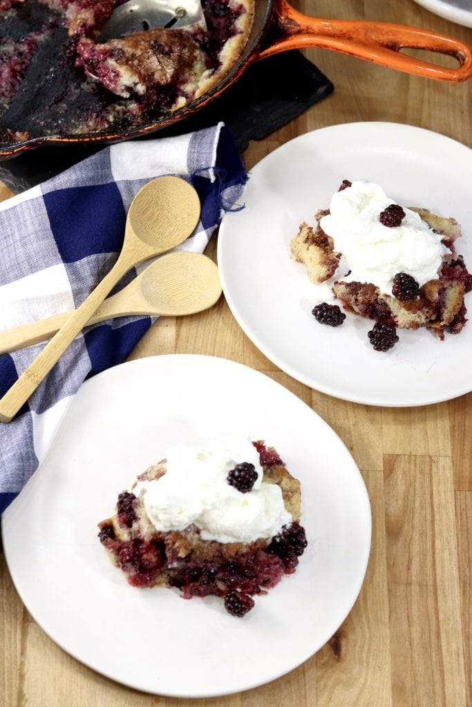 Blackberry Cobbler with whipped cream on 2 white saucers