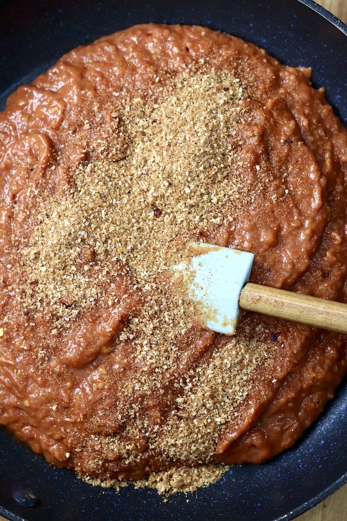 Tomato sauce in a skillet sprinkled with spices - spatula in the sauce