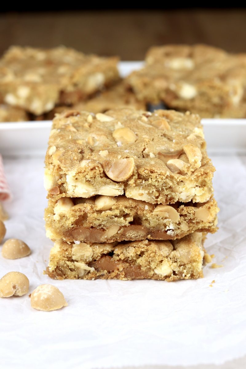 Caramel white chocolate macadamia nut bars stacked 3 on a plate
