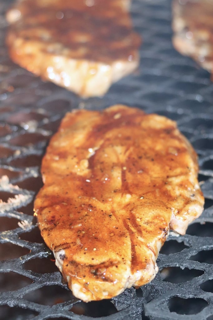 pork steaks on the grill with peach bbq sauce