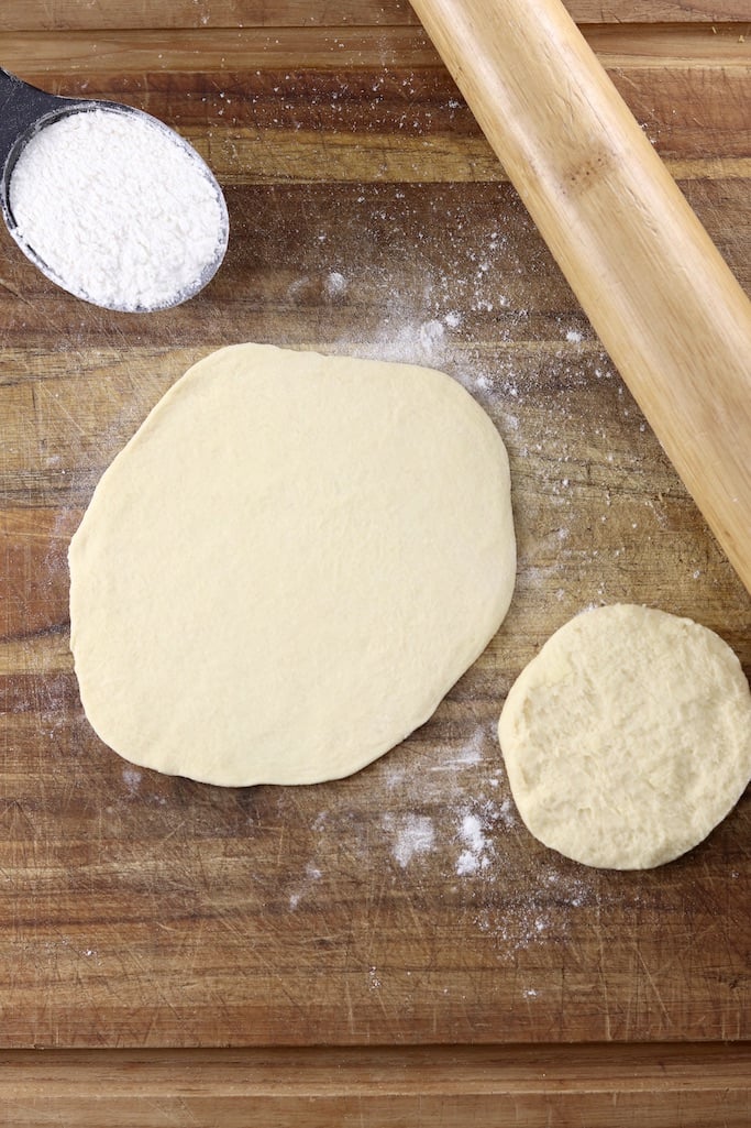 can biscuit dough rolled out on a cutting board with rolling pin for pizza