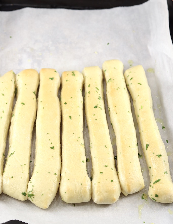 Breadsticks with garlic butter on white parchment paper