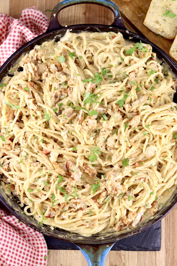 Skillet of cheesy chicken spaghetti garnished with parsley