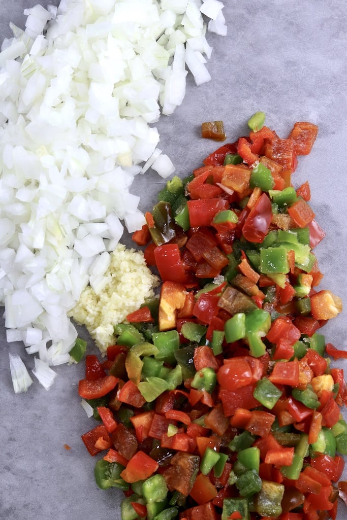 Diced onions, garlic and red and green peppers on a gray cutting board