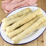 Homemade Breadsticks on an oval platter with red check napkin
