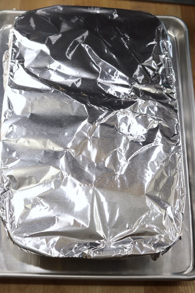 Casserole covered in aluminum foil on a sheet pan