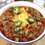 Chili in a bowl with cheese and jalapenos, close up