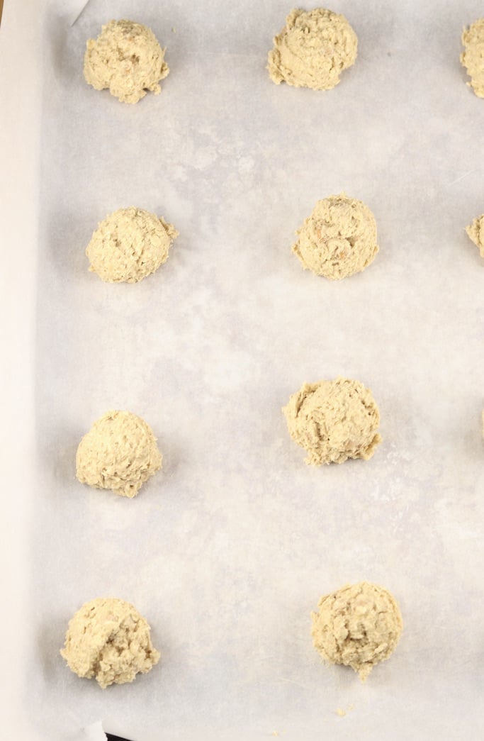 Cookie dough balls on white parchment paper lined baking sheet -overhead view
