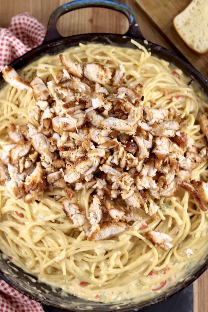 Diced chicken over skillet of cheesy spaghetti