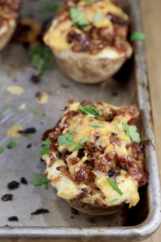 Twice baked potatoes with pulled pork on a sheet pan, close up view