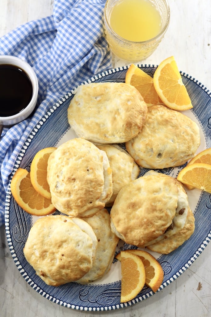 Air Fryer Sausage Biscuits on a platter with slices of fresh oranges, coffee and juice