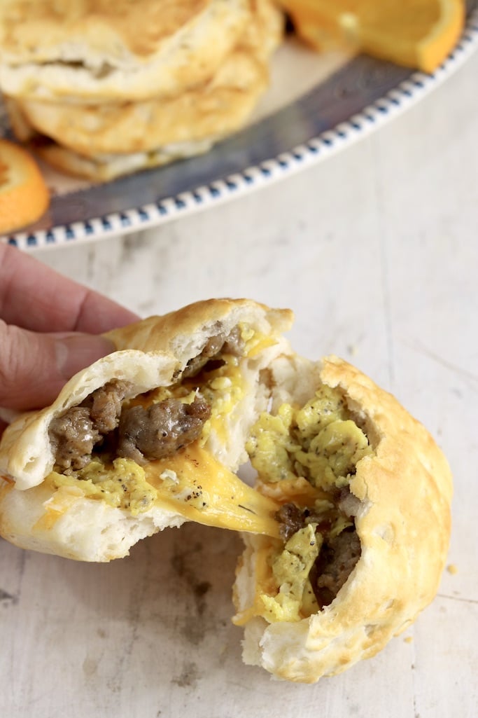 biscuit split in half with melted cheese, eggs and sausage