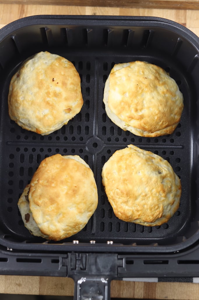 air fryer basket with cooked biscuit sandwiches