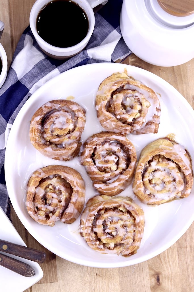 Cinnamon rolls on a white plate, with cup of coffee and small coffee pot