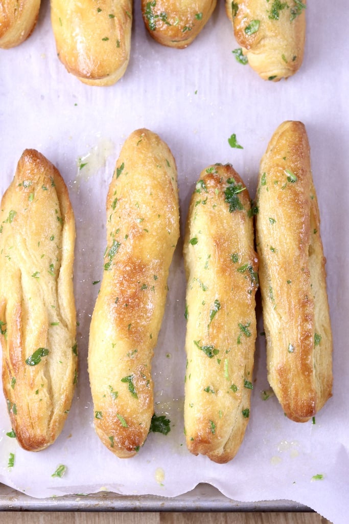 Breadsticks brushed with garlic butter on parchment paper