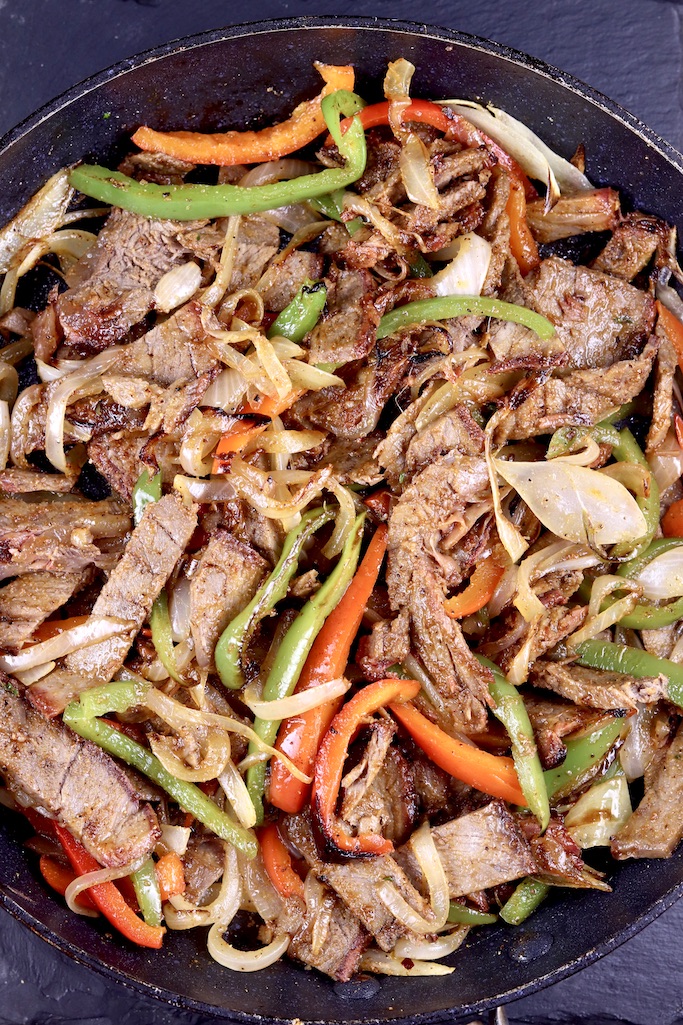 Skillet of cheesesteak mixture with beef, peppers and onions