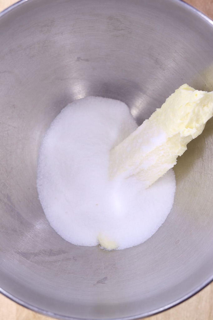 Sugar and a stick of butter in a silver mixer bowl