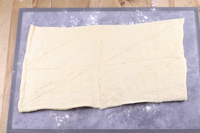 Crescent dough on a floured cutting board, unrolled into a rectangle