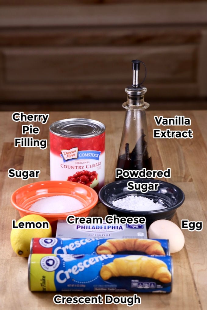 Ingredients for Cherry Cheese Danish with text labels: crescent dough, sugar, powdered sugar, vanilla, lemon, egg, cream cheese, cherry pie filling