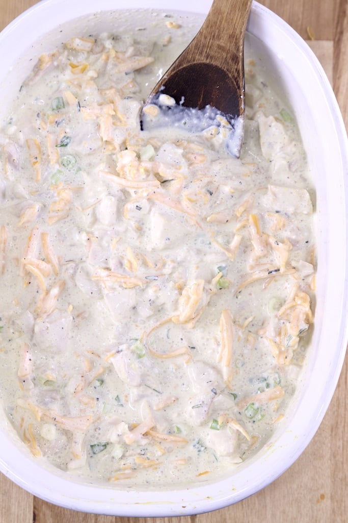 Casserole dish with chicken, cheese and creamy sauce with wood spoon