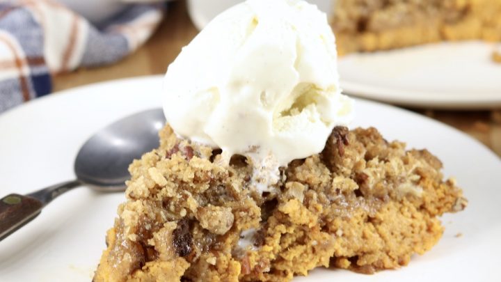 Pumpkin Pecan Crisp topped with ice cream on a white plate with spoon