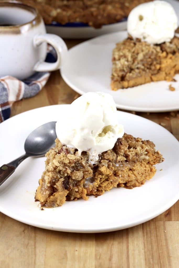 Slices of pumpkin crisp topped with vanilla ice cream, 2 servings on white plates