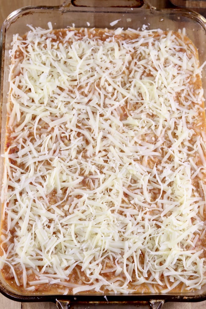 shredded cheese sprinkled over pan of manicotti