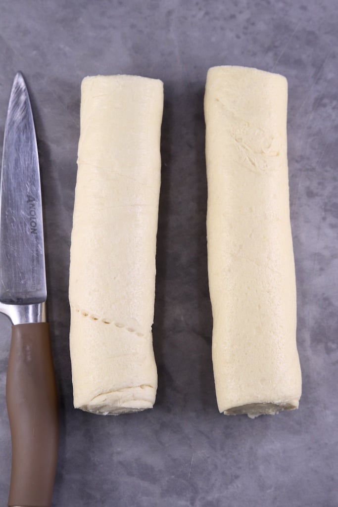 2 rolls of refrigerated crescent dough on a cutting board with a knife