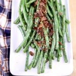 bacon green beans on a white platter with plaid napkin