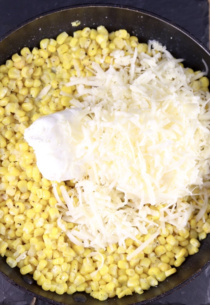 skillet of corn with cream cheese and shredded white cheddar cheese