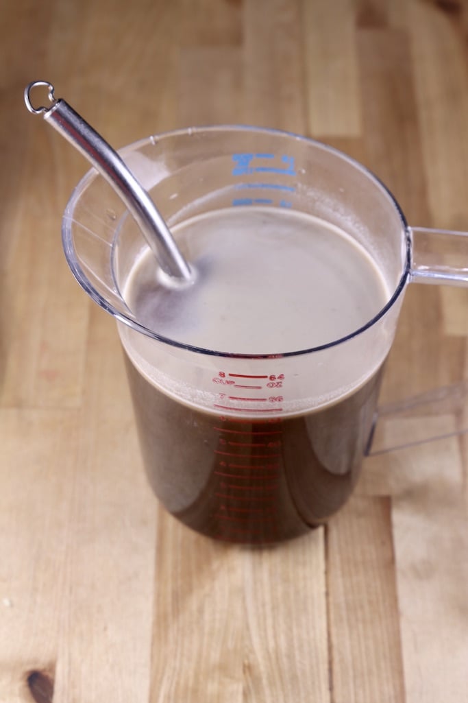 beef broth in a measuring pitcher with whisk