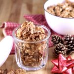 Candied Walnuts in a small jar for a gift, pine cones and red bow with a white bowl of walnuts