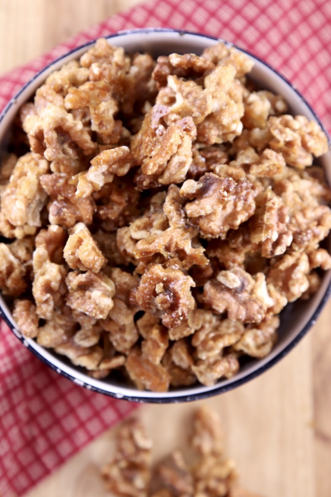 Overhead view of bowl of candied walnuts with red napkin