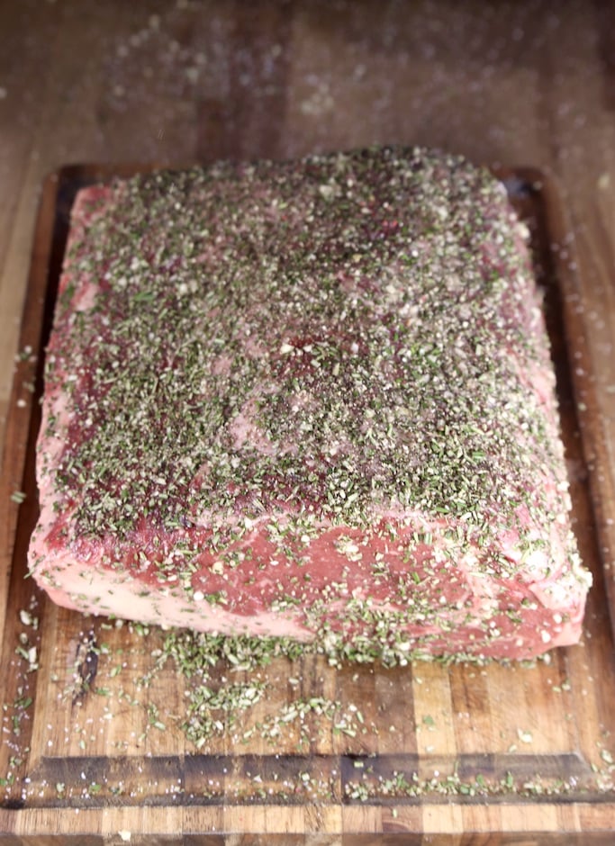 Prime rib roast seasoned with garlic and rosemary rub on a cutting board ready to grill or roast