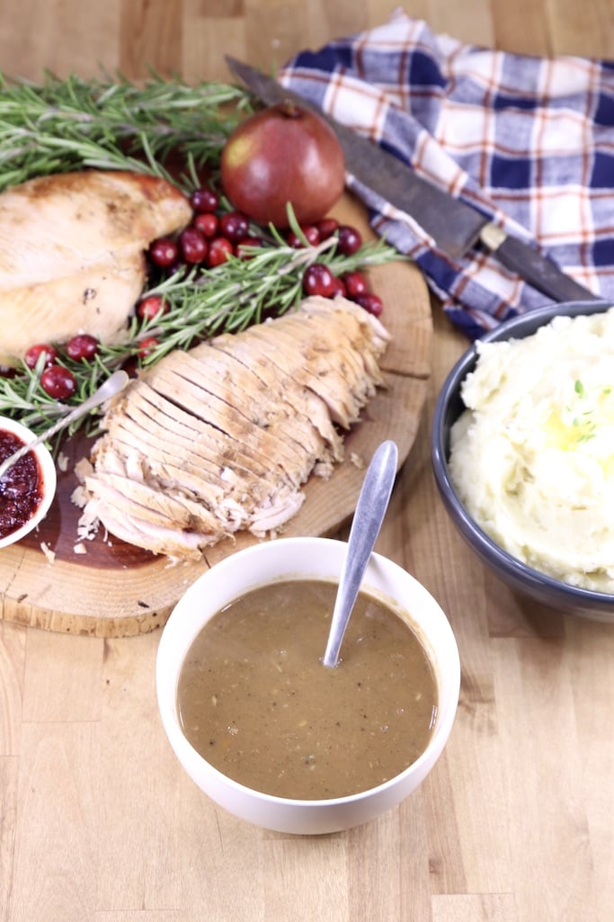 Bowl of gravy, platter of sliced turkey breast, mashed potatoes