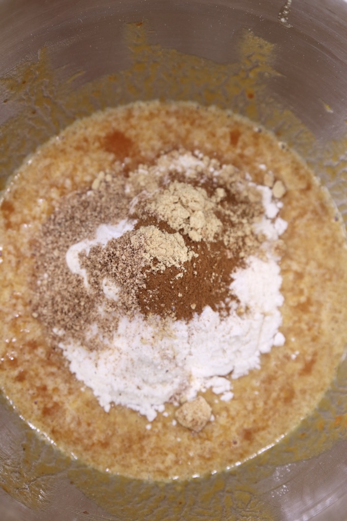 Flour, cinnamon, nutmeg added to mixing bowl with pumpkin for cake roll