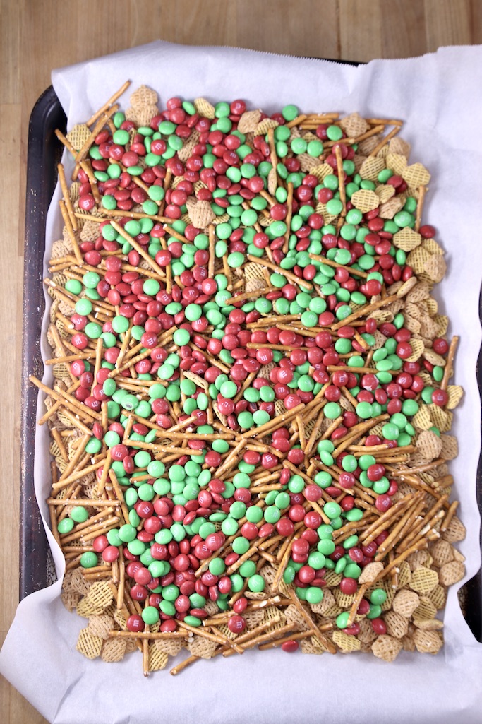 Parchment lined baking sheet with pretzels, cereal and m&m's