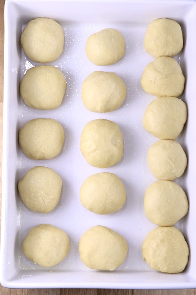 White baking pan filled with dinner roll dough ready to rise